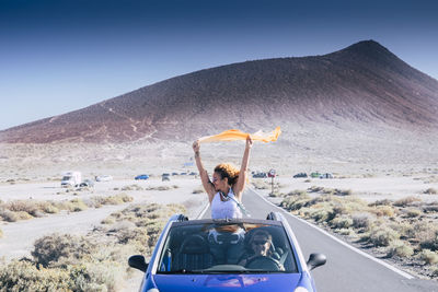 Rear view of woman with umbrella on land against sky