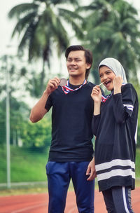 Happy athletes with medals standing on sports track