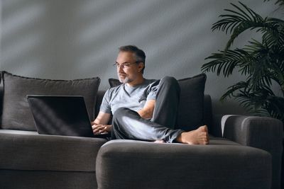 Man using laptop while sitting on sofa at home