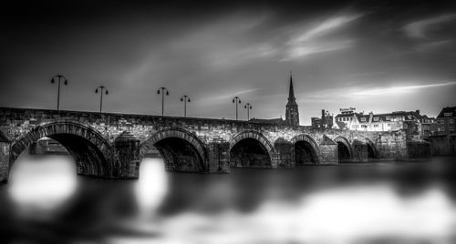 Bridge over river against cloudy sky