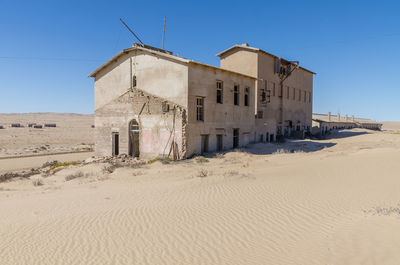 Abandoned buiding on desert against clear blue sky at former german ghost town kolmanskop, namibia