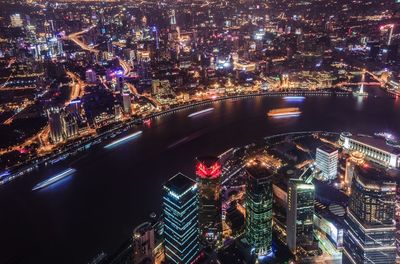 High angle view of river amidst illuminated buildings in city