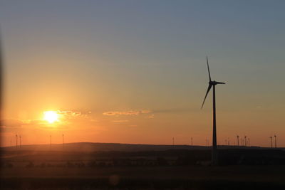 Silhouette of wind turbines on field