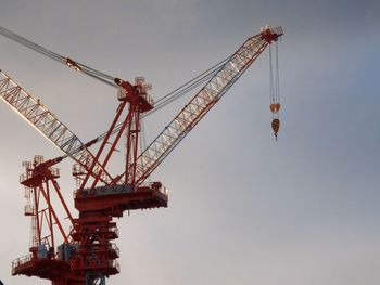 Low angle view of cranes against sky