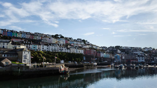 Buildings by river against sky in town