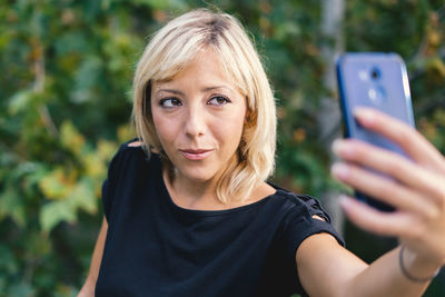 Blond woman taking selfie with mobile phone