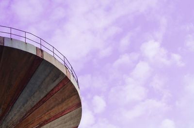 Low angle view of storage tank against cloudy sky