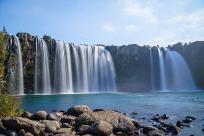 Scenic view of waterfall against sky