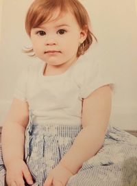 Portrait of cute girl sitting on bed at home