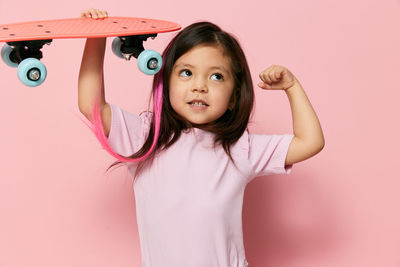 Girl holding skateboard flexing muscles