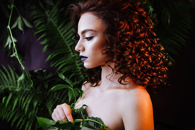 Beautiful redhead woman wearing make-up by plants