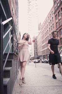 Full length portrait of woman standing against buildings in city