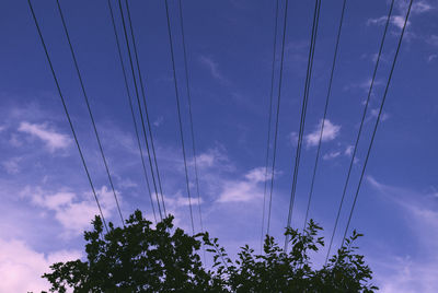 Low angle view of electricity pylon against blue sky