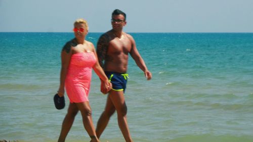 Friends standing on beach against clear sky