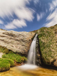 Scenic view of waterfall against sky