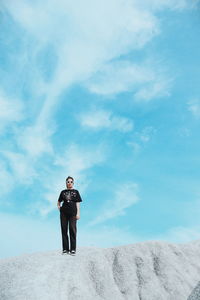 Low angle view of man standing on street against sky