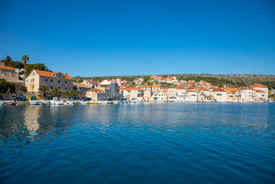 View of townscape by sea against blue sky