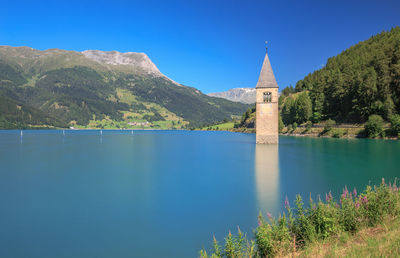 Scenic view of lake and mountains against clear blue sky