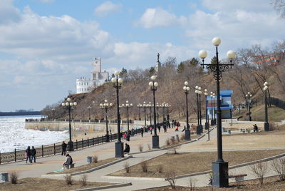 People on street by sea against sky