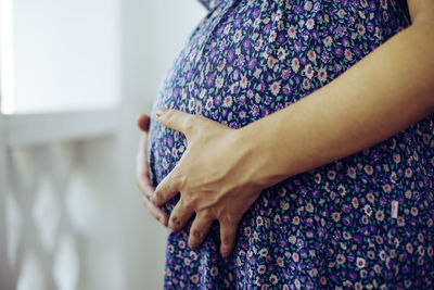 Midsection of woman standing against purple wall