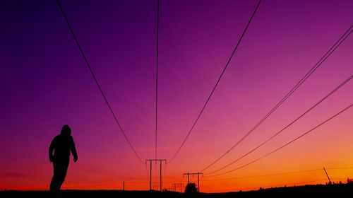 Silhouette man standing against orange sky during sunset