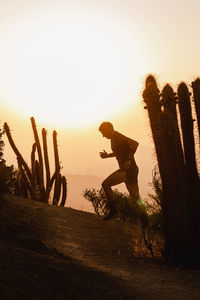 Rear view of woman standing against sky during sunset