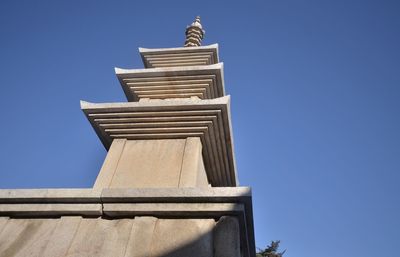 Low angle view of statue against building against clear blue sky