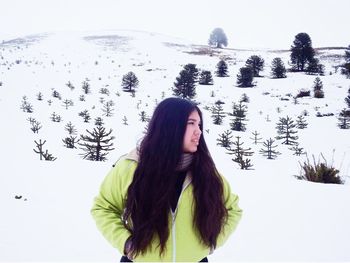 Young woman in warm clothing standing on snow covered landscape