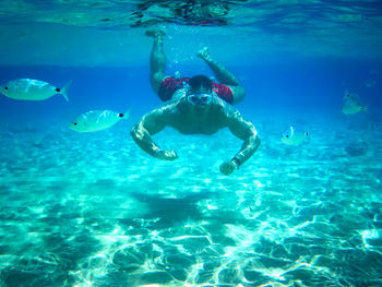 Man swimming undersea by fish