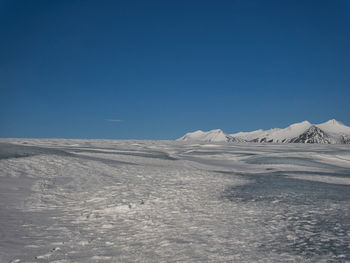 Scenic view of snowcapped landscape against clear blue sky