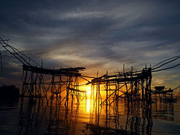 Silhouette pier by sea against sky during sunset