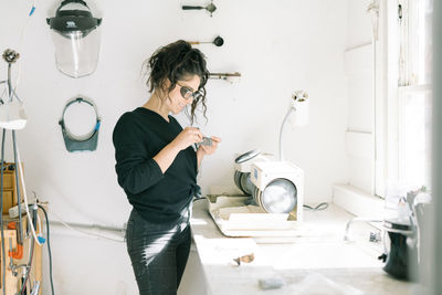 Female jeweler smiles with satisfaction while working in home studio