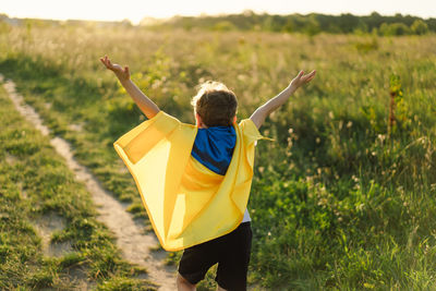 Ukrainian child boy in white t shirt with yellow and blue flag of ukraine in field.