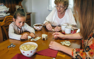 Close-up of family playing dominoes while having food at table