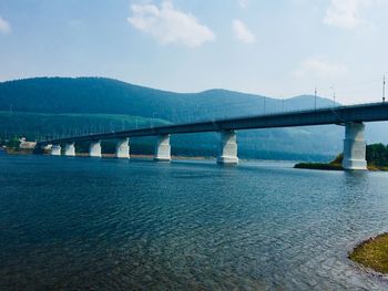 Bridge over calm river against sky