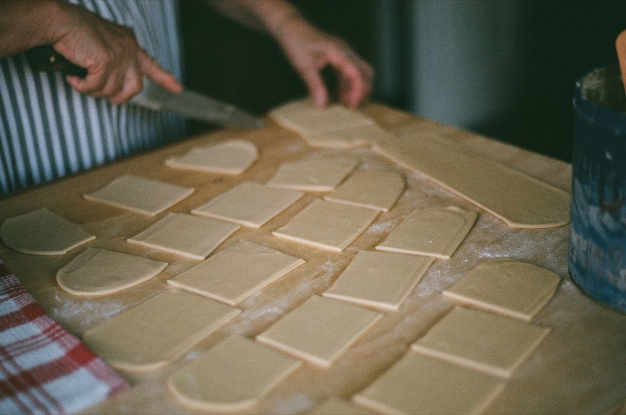 CLOSE-UP OF PERSON PREPARING FOOD AT KITCHEN