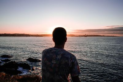 Rear view of man looking at sea against sky