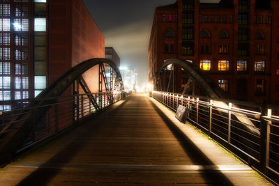 Footbridge amidst buildings in city at night