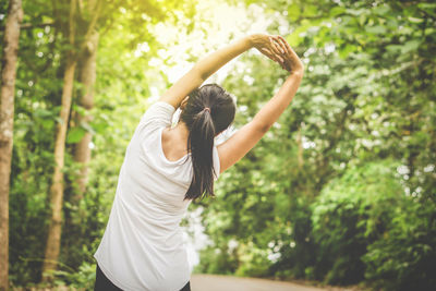 Rear view of woman exercising against trees