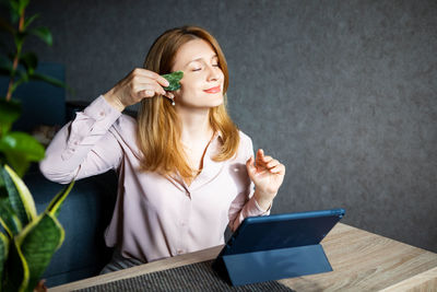 Young woman using phone while sitting on table