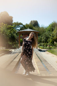 Portrait of young woman standing by fountain