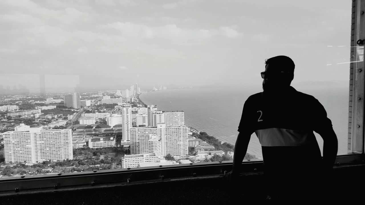 REAR VIEW OF MAN STANDING IN CITY