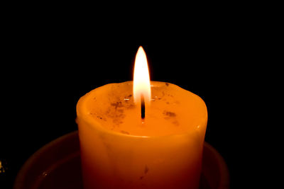 Close-up of lit candle against black background