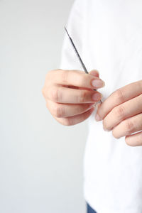 Close-up of hand holding thermometer against white background