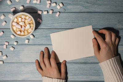 Cropped hands of woman writing in book on table