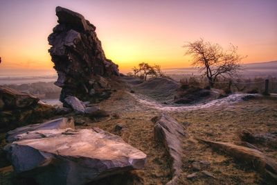 Rocks on land against sky during sunset