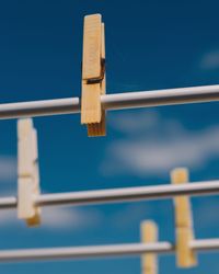 Close-up of clothespins on rope against blue sky