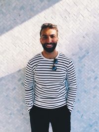 Portrait of young man standing against wall