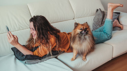 Young woman with dog relaxing on bed at home
