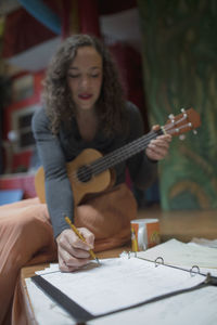 Young female musician composing music with the ukulele
